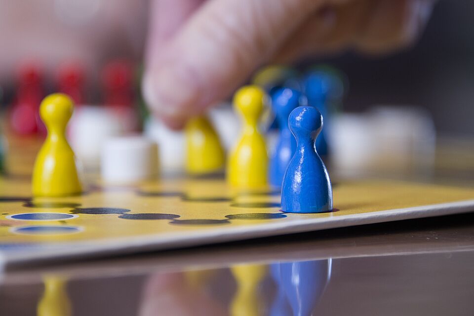 Das Bild zeigt ein Mensch-Ärgere-Dich-Nicht Spielbrett, auf welchem gespielt wird.